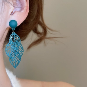 Close-up of matte forest green hollow leaf tassel earrings on a model in vintage style