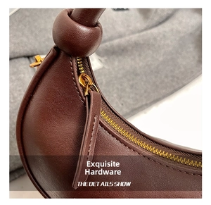 Detailed close-up of golden metal zipper and knotted leather handle on a brown hobo bag