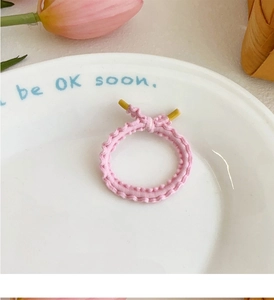 Detail of pink wavy elastic hair tie with yellow tip decoration on a ceramic tray
