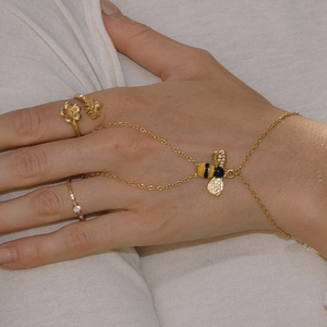 Detailaufnahme von Bienen-Goldarmband und Ringset mit Emaille- und Kristallakzenten