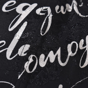 Macro view of black fabric texture featuring white artistic cursive font pattern