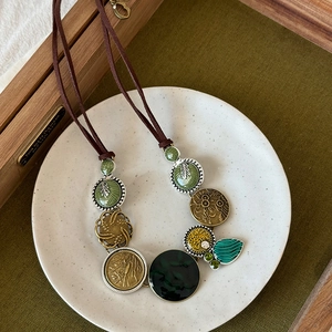 Detailed close-up of retro butterfly pendants with enamel inlay on a dark suede cord