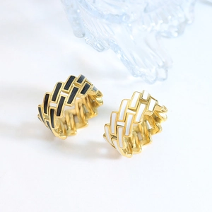 Minimalist geometric gold rings with black and white enamel details on white background