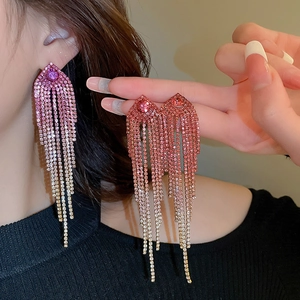 Detail of elegant pink gradient rhinestone tassel earrings worn by a female model