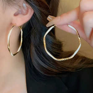 Artistic gold and white enamel irregular hoop earrings with textured vintage finish