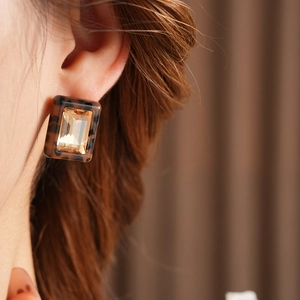 Close-up of square leopard print resin earrings with amber gemstones on a model