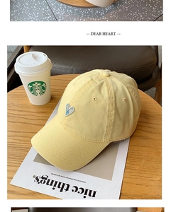 Close-up of yellow canvas baseball cap with blue and white heart embroidery detail