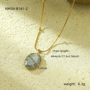 Detail of grey oval natural stone pendant with golden beaded stainless steel chain