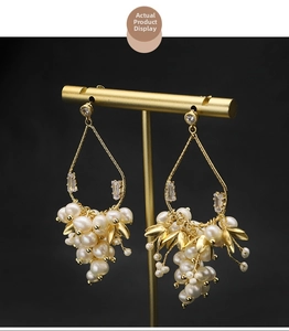 Détail macro de boucles d'oreilles perles vintage avec feuilles dorées et zircon sur socle