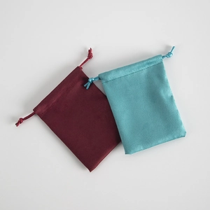 Detail of burgundy and teal velvet drawstring jewelry bags with soft fabric texture