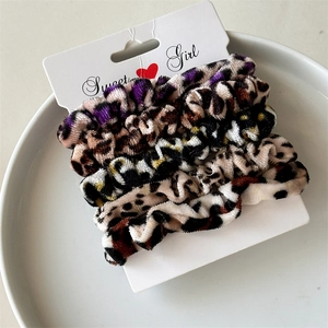 Set of 4 soft velvet leopard print scrunchies displayed on a Sweet Girl card packaging