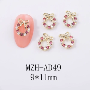 Christmas nail art charm with golden bow, pearls and pink rhinestones in wreath design