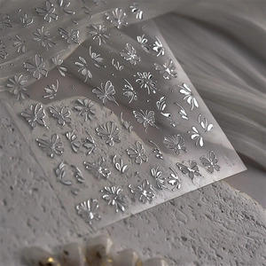 Macro view of silver metallic embossed butterfly and flower nail art stickers