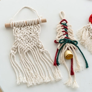 Handmade macrame Christmas tree ornament with wooden stick and bells on white background