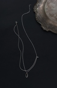 Détail du collier double couche en acier titane argenté avec pendentif ovale chic