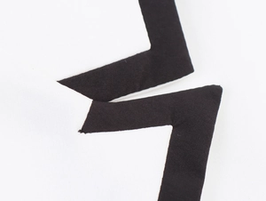 Détail macro de la couture contrastée noir et blanc sur le gilet de costume sans manches