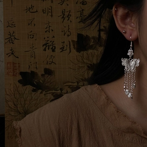 Close-up of silver hollow butterfly tassel earrings with long metallic fringe charms