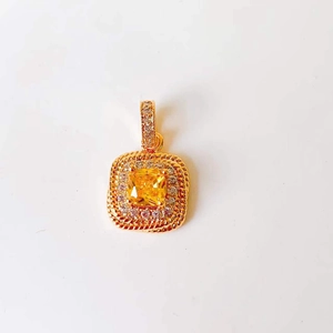 Macro detail of square gold pendant with yellow center stone and clear zircon accents