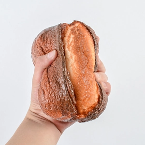Realistic soft PU artificial bread loaf squishy toy showing slow rebound compression detail