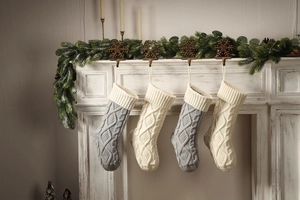 Detail of grey and cream knitted Christmas stockings with cable patterns hanging on a mantel