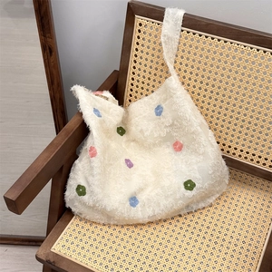 Detail of white fringe lace shoulder bag with colorful floral embroidery on a wooden chair