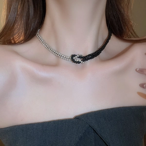 Dettaglio di una collana y2k con perle nere e cristalli argentati indossata sul collo