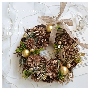 Close-up of Christmas wreath with pine cones and golden baubles on a vintage book