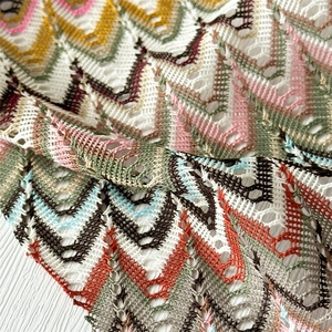 Macro shot of knitted wave pattern fabric with hollow texture and multicolor details