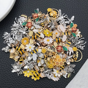 Macro view of detailed enamel bee and daisy charms for DIY jewelry making and crafts