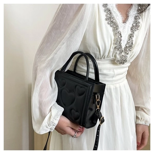 Détail du sac noir en similicuir avec motif cœur surpiqué et détails dorés brillants