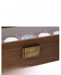 Close-up of walnut wood watch box featuring a vintage metal lock and clear display window