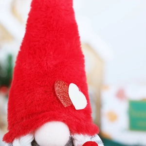 Detail of red plush gnome hat with glittery heart patterns and soft grey beard texture