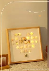 Detail of DIY heart seashell photo frame night light with warm LED lights on a lace surface