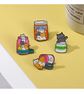Close-up of cat medicine bottle enamel pins with Happy Pills text and metal finish