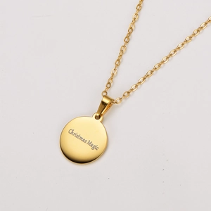 Detailed view of gold round pendant with Christmas Magic engraving on a minimalist necklace
