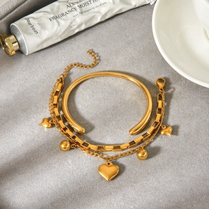 Detalle del elegante conjunto de pulsera con dije de corazón y brazalete oro 18k.