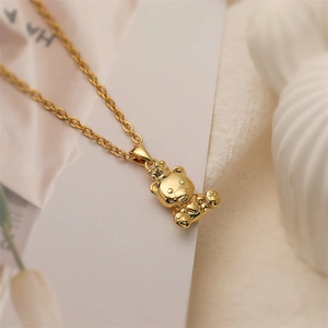 Dettaglio della collana dorata con ciondolo a forma di orso con corona su tessuto