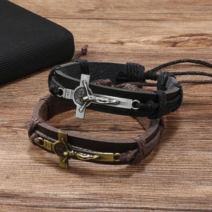 Detailed close-up of woven leather bracelets with metal cross charms on wooden surface