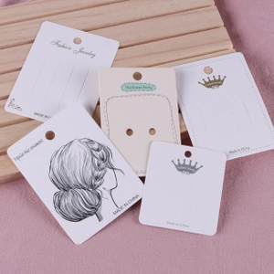 Detail of white jewelry display cards for hair accessories on a wood background