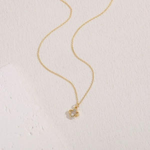 Detail of clover pendant with sparkling zircon inlays on a golden chain necklace
