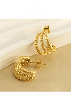 Detail of 18K gold-plated triple hoop earrings with hammered texture on white stairs