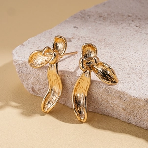 Detailed view of golden leaf-shaped earrings with hand-hammered texture on stone surface