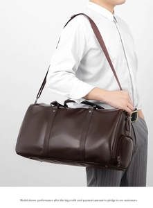 Brown faux leather duffel bag with pebble texture and adjustable shoulder strap worn by model