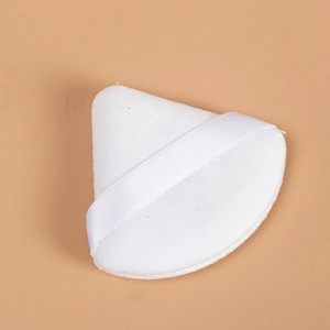 Dettaglio macro di un piumino da cipria triangolare bianco in velluto con nastro di raso