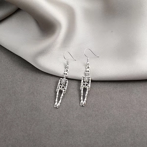 Dettaglio macro di orecchini a scheletro in argento vintage su seta bianca lucida