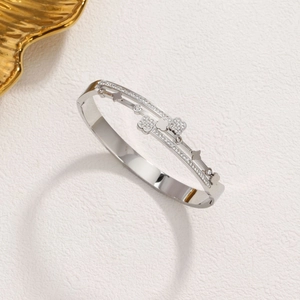 Elegant silver-tone clover bangle with zircon stones on a clean textured background