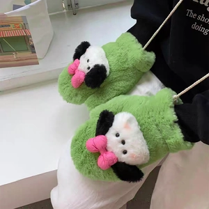 Close-up of green plush mittens featuring a cute cartoon dog with a pink 3D bow detail