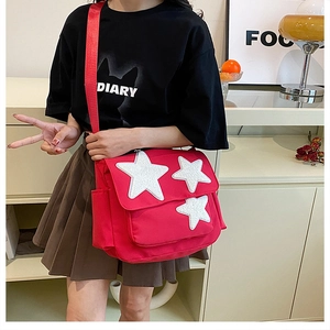 Pink canvas messenger bag with sparkling star patches and wide shoulder strap