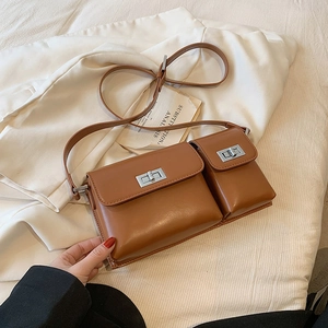Detail of brown leather crossbody bag with silver twist locks on white fabric