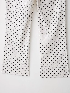 Detailaufnahme von weißem Stoff mit schwarzen Punkten und Saumnaht an der Schlaghose